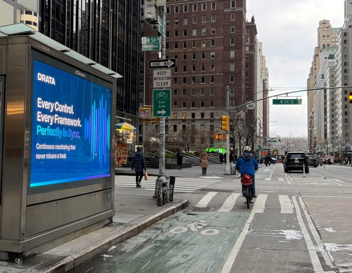 Drata urban panel at W 54th St with cyclist passing in NYC bike lane