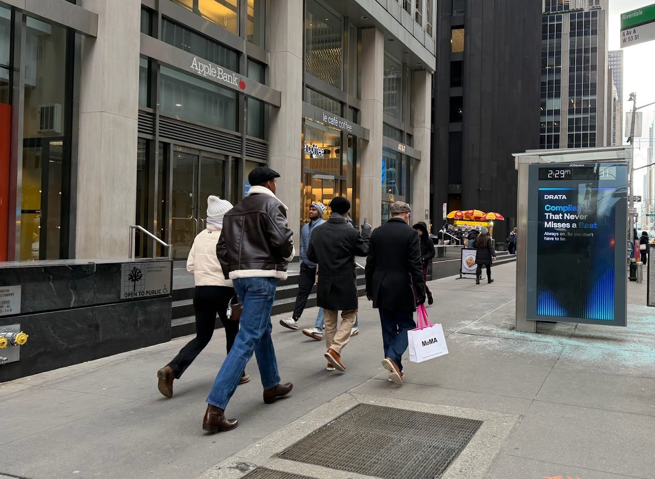 Drata compliance JCDecaux urban panel at 6th Avenue and West 53rd Street in Midtown Manhattan — B2B SaaS account-based campaign placement