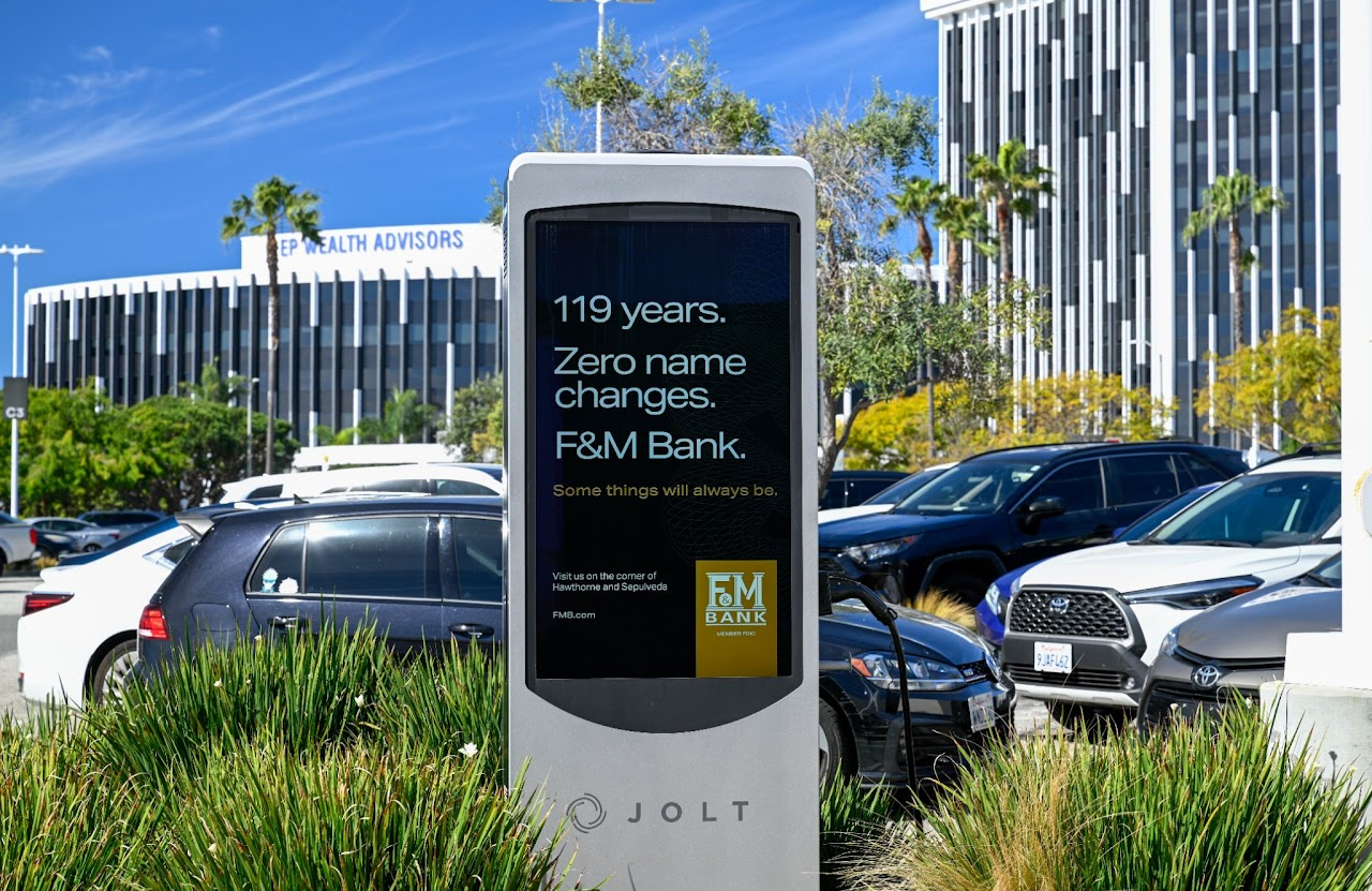 F&M Bank brand creative on an EV-charging station screen near an office park.