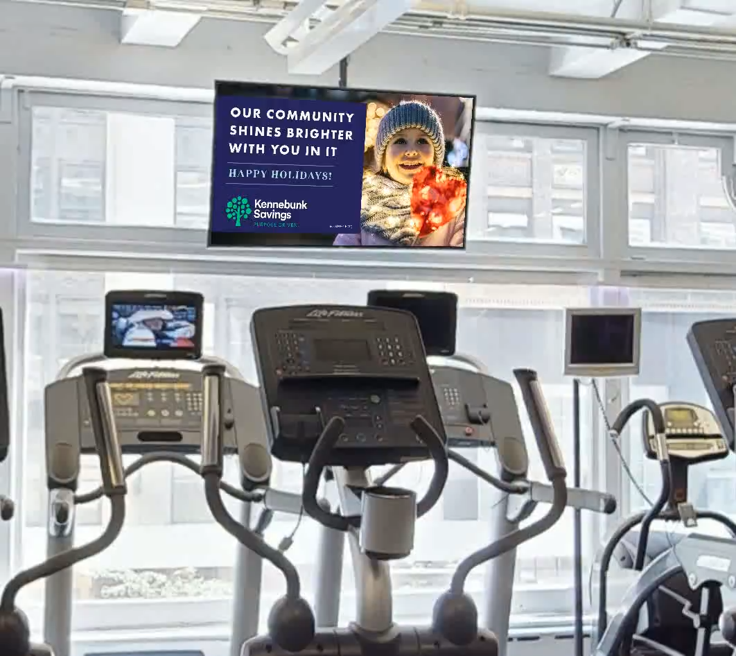 Kennebunk Savings community creative on a gym cardio-deck screen.