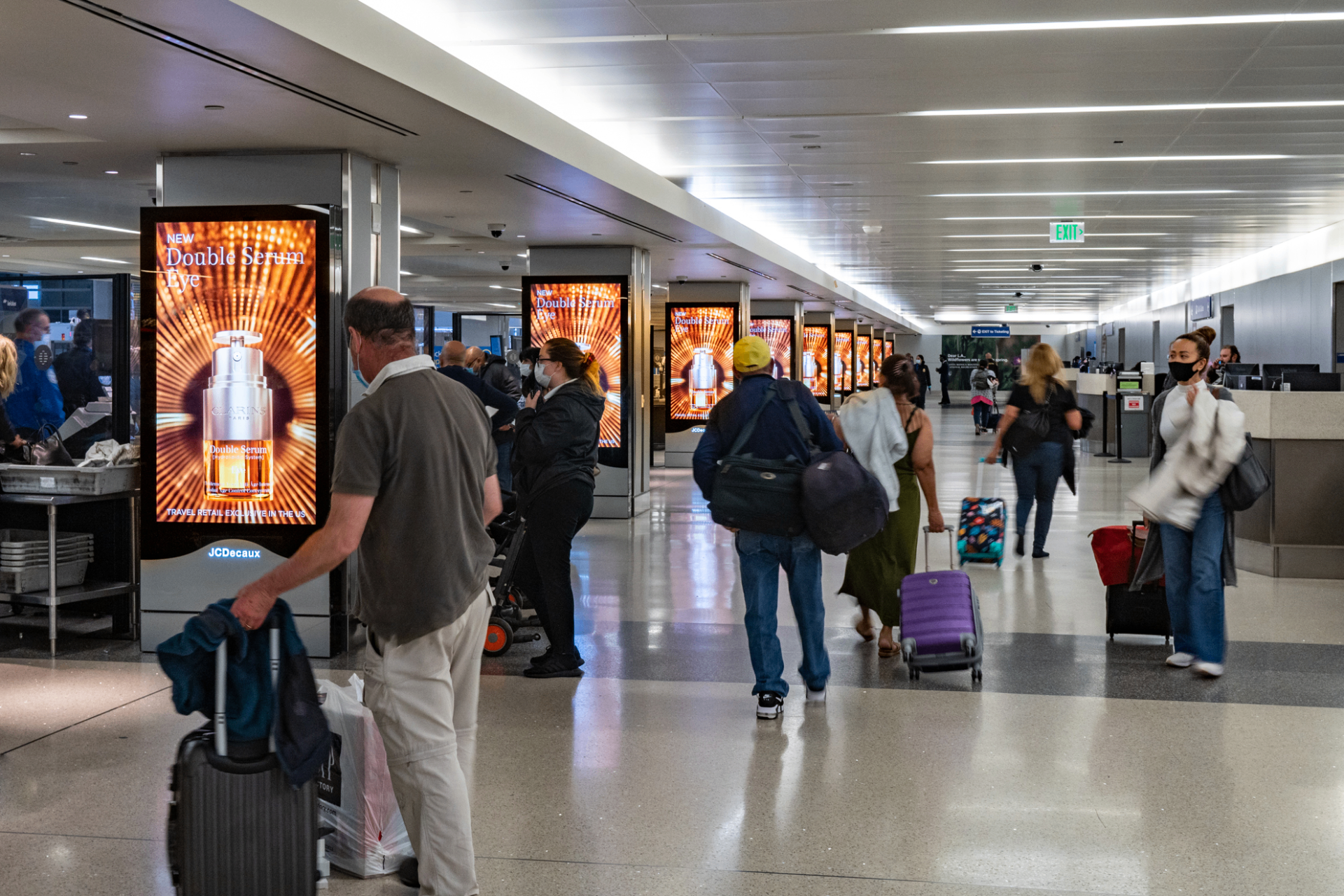 Digital screens lining an airport terminal as travelers arrive — the first impression of the conference city.